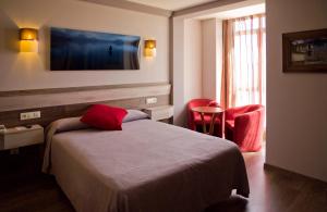 プエブラ・デ・サナブリアにあるHotel Gran Casona de Sanabriaのベッドと赤い椅子が備わるホテルルームです。