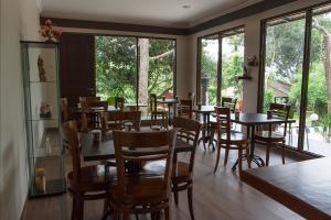 a dining room with tables and chairs and windows at Villa Sawah Resort Managed by Salak Hospitality in Bogor
