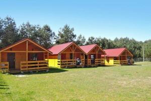 rząd drewnianych domków z czerwonymi dachami na polu w obiekcie Domki nad morzem - Wisełka w Wisełce