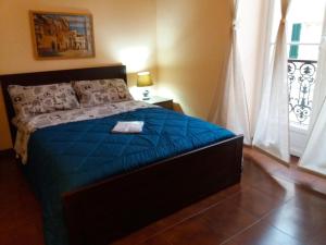 Schlafzimmer mit einem Bett mit blauer Bettwäsche und einem Fenster in der Unterkunft Matteotti in Sanremo