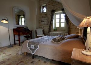 a bedroom with a bed and a table and a mirror at Mas Bella Cortis in La Garde-Adhémar