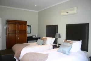 a bedroom with two beds and a desk with a lamp at Eshowe Hills Golf Estate in Eshowe