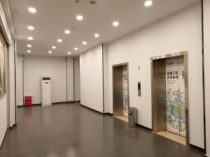 鄭州的住宿－7天優品·鄭州經三路世紀聯華店，一条带白色墙壁和银色电梯的走廊