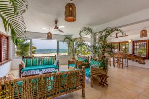 Tequila Sunrise Beach Cabana - Diani Beach في شاطئ دياني: غرفة معيشة مع كراسي وطاولات وإطلالة على المحيط