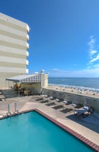 a swimming pool with chairs and the beach at Beach Quarters Resort in Virginia Beach