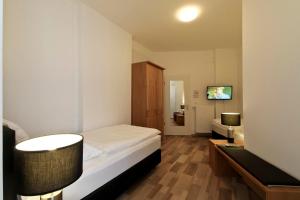 a bedroom with a bed and a desk with two lamps at Hotel Jammerkrug in Gladbeck