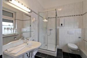 a bathroom with a sink and a shower and a toilet at Hotel Jammerkrug in Gladbeck