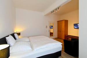 Schlafzimmer mit einem weißen Bett und einem TV in der Unterkunft Hotel Jammerkrug in Gladbeck