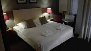 sypialnia z dużym białym łóżkiem z 2 ręcznikami w obiekcie Villa Le Matin w mieście Konstancin-Jeziorna
