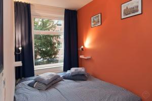 a bedroom with an orange wall and a bed with two pillows at B&B West City Amsterdam in Amsterdam