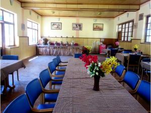a long table with a vase of flowers in a room at Hotel Abu Palace in Leh