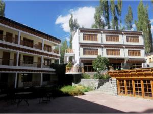 a large white building with tables and chairs in a courtyard at Hotel Abu Palace in Leh