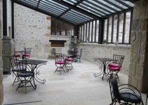 un grupo de mesas y sillas en una habitación con ventanas en Mas Bella Cortis, en La Garde-Adhémar