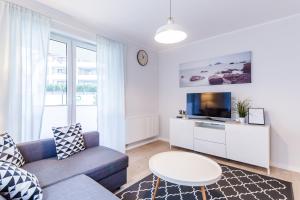 a living room with a couch and a tv at Equilibrium Apartments in Ustronie Morskie