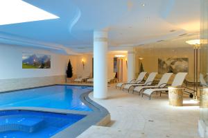 una piscina in un hotel con sedie intorno di Hotel Teresa a San Vigilio Di Marebbe