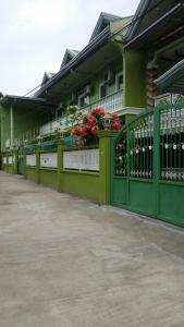 ein grüner Zaun vor einem Haus mit Blumen in der Unterkunft Magdalene Apartment in Balamban