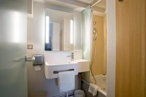 a bathroom with a sink, toilet and mirror at B&B HOTEL Moulins in Toulon-sur-Allier