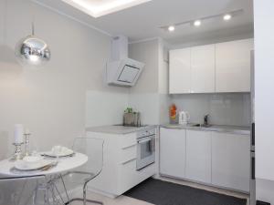 グダニスクにあるApartament Garnizonの白いキャビネットと小さなテーブル付きのキッチンが備わります。