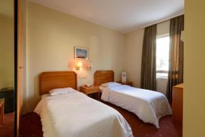 a hotel room with two beds and a window at Congo Palace in Athens
