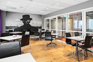 a dining room with tables and a man in a top hat at Sure Hotel by Best Western Stockholm Alvsjo in Stockholm