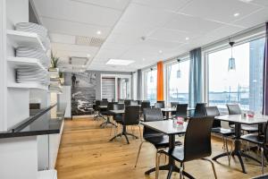 a dining room with tables and chairs and large windows at Sure Hotel by Best Western Stockholm Alvsjo in Stockholm