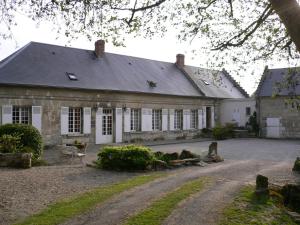 un grand bâtiment en pierre avec des fenêtres blanches et une allée. dans l'établissement Le Moulin De Laval, à Cuisy-en-Almont