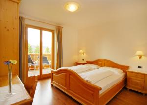 a bedroom with a large wooden bed and a balcony at Urthalerhof in Castelrotto