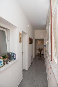 a hallway with white walls and white floors and windows at Rooms Vendi in Daruvar