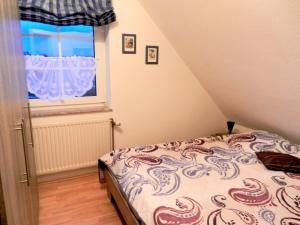 Schlafzimmer mit einem Bett und einem Fenster in der Unterkunft Ferienwohnung Friesennest Greetsiel 1 in Krummhörn