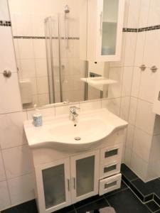 ein weißes Badezimmer mit einem Waschbecken und einem Spiegel in der Unterkunft Ferienwohnung Friesennest Greetsiel 1 in Krummhörn