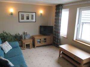 un soggiorno con divano blu e TV di Apartment 76 a Kirkwall