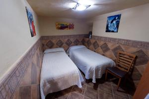 アンテケラにあるApartamento Antequeraの小さなベッドルーム(ベッド2台、椅子付)