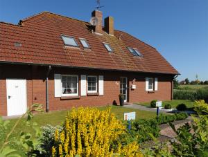 ein Backsteinhaus mit rotem Dach und gelben Blumen in der Unterkunft Ferienwohnung Friesennest Greetsiel 1 in Krummhörn
