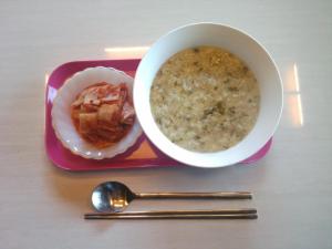 einen Teller Essen mit einer Schüssel Suppe und einem Löffel in der Unterkunft Guesthouse Kim's Cabin in Seogwipo