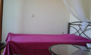 a room with a glass table and a purple blanket at House in Front of the Sea in Nea Fokea