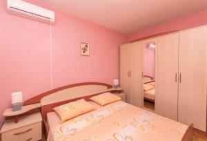 una habitación con paredes rosas y una cama con almohadas amarillas en Apartments Albina, en Brodarica