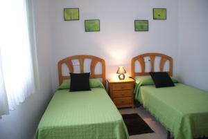 two beds in a room with green sheets at Casa Miami Playa in Miami Platja