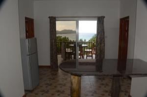 a kitchen with a table and a refrigerator and a balcony at Mirella Villa Island Princess Villa in Praslin