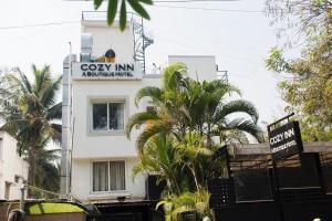 un edificio blanco con un cartel que lee apartamentos acogedores de posada en Hotel Cozy Inn, en Pune