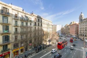 a red double decker bus driving down a city street at Fisa Rentals Ramblas Apartments in Barcelona