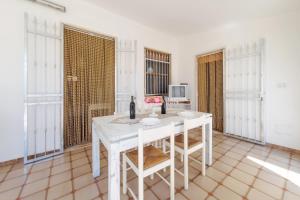 a white table and chairs in a room with windows at Villetta Martino Guest House in Torre Chianca