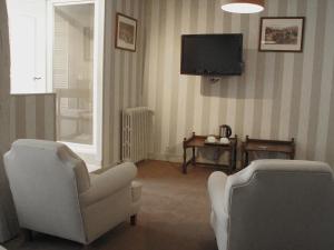 uma sala de estar com duas cadeiras e uma televisão em Hôtel La Licorne & Spa em Lyons-la-Forêt