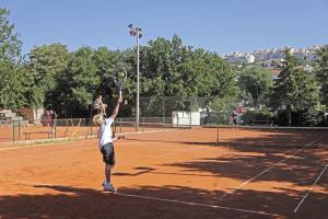 a person serving a tennis ball on a tennis court at Garfild Guest house in Novi Vinodolski
