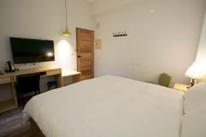 a bedroom with a bed and a desk with a television at Free wind B&B in Taitung City