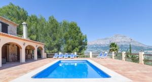 a swimming pool with chairs and a house at Pura Vida in Jávea