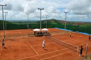a group of people playing tennis on a tennis court at Pousada Villas da Serra in Serra de São Bento