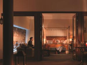 a man sitting in a living room next to a bed at Palacio Nazarenas, A Belmond Hotel, Cusco in Cusco