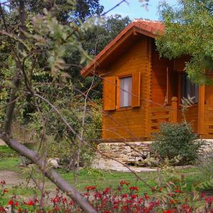 a wooden cabin in a garden with flowers at Cabañas del Cortino in Monleras