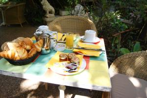 a picnic table with a basket of bread and orange juice at Le Windsor, Jungle Art Hotel in Nice