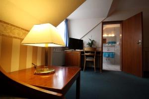 a room with a table with a lamp and a kitchen at Hotel Burg-Mühle in Gelnhausen